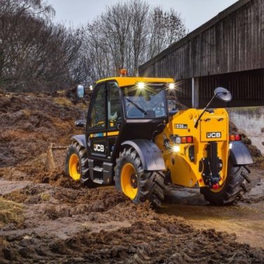 JCB handler cleaning up manure in farm yard
