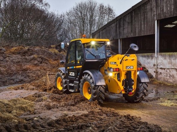 JCB handler cleaning up manure in farm yard