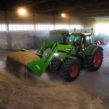 Fendt tractor picking up grain in a storage shed