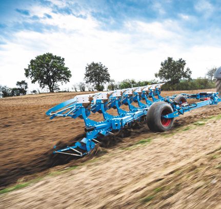 Plough being dragged through a field by a tractor
